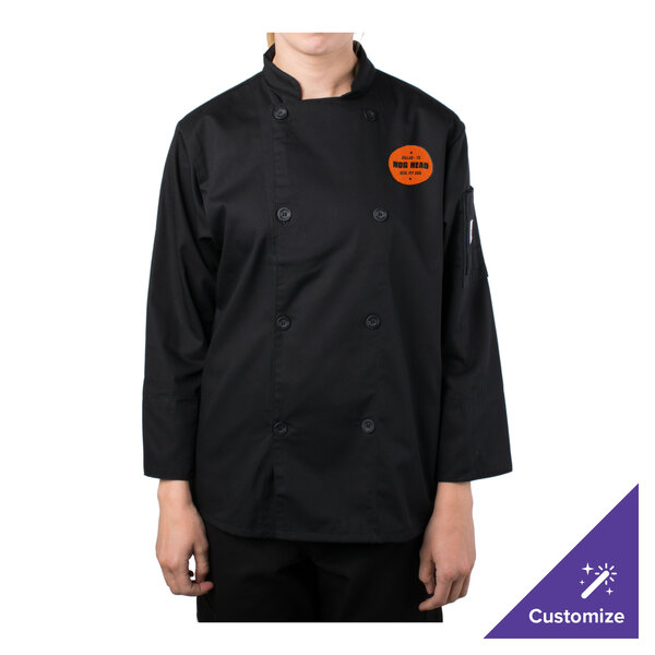 A woman in a black Mercer Culinary chef's jacket with an orange logo on a counter in a professional kitchen.