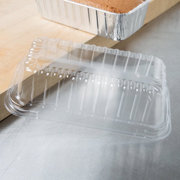A clear plastic container with a foil bread loaf inside.