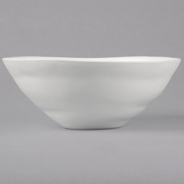 A close-up of a white 10 Strawberry Street stoneware serving bowl with a curved edge.