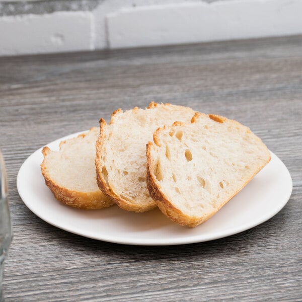 A 10 Strawberry Street white stoneware plate with a piece of bread on it.