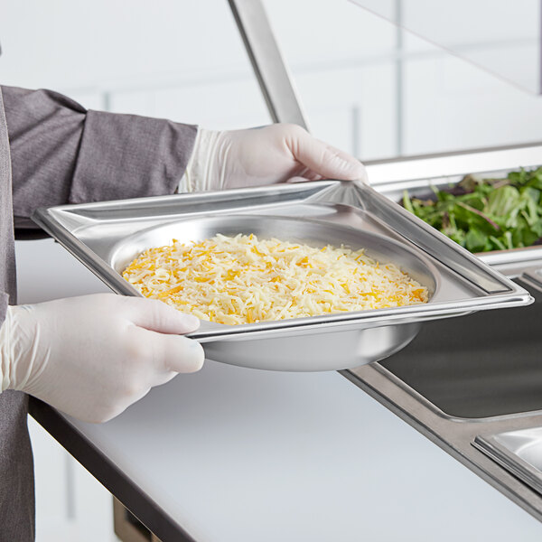 A person holding a Vollrath stainless steel metal tray with food.