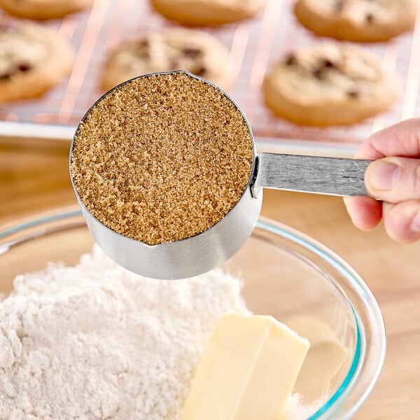 A hand using a measuring cup to scoop Golden Barrel Organic Light Brown Sugar