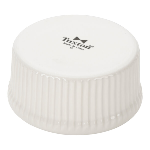 A white fluted china ramekin turned upside down, showing the Tuxton brand on the bottom.
