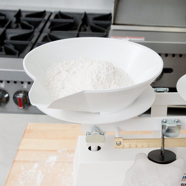 A white Cardinal Detecto scale scoop with flour in it.
