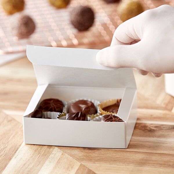 A hand holding a white 1/4 lb. candy box.