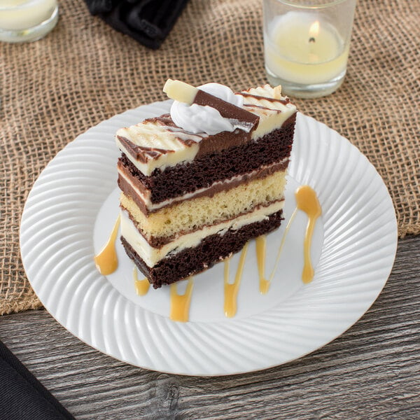 A slice of cake on a Visions Wave ivory plastic plate with a candle.