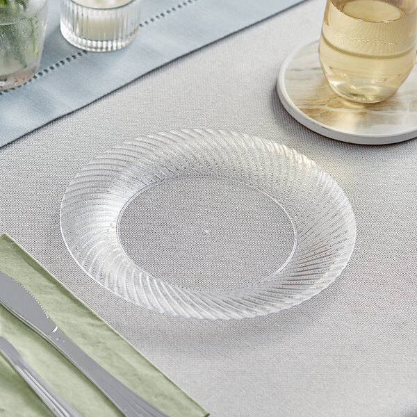 A Visions clear plastic plate with a knife on it on a table.