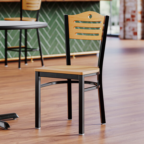 A Lancaster Table & Seating wooden side chair with a natural wood seat and back on a restaurant floor.