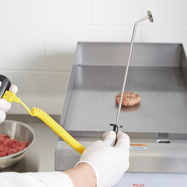 A person using a Taylor hamburger surface probe to measure ground beef.