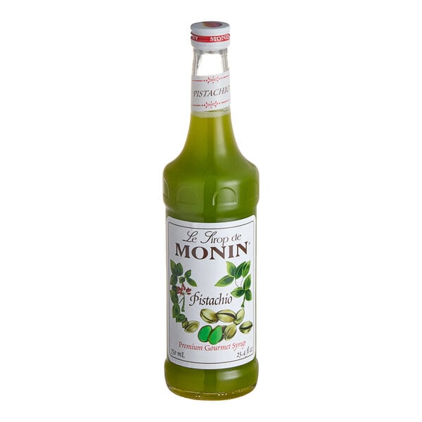 A Monin 750 mL bottle of green Pistachio flavoring syrup with a white label.