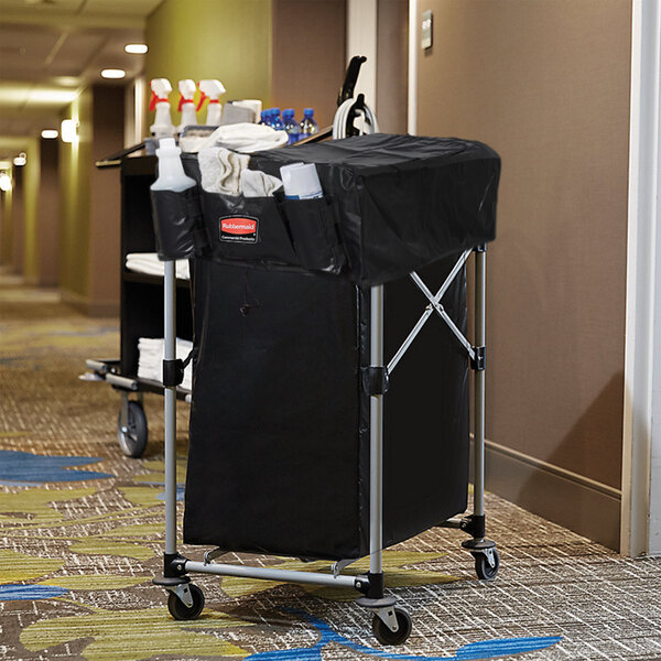 A Rubbermaid laundry cart with a black cover and bag on a metal frame.