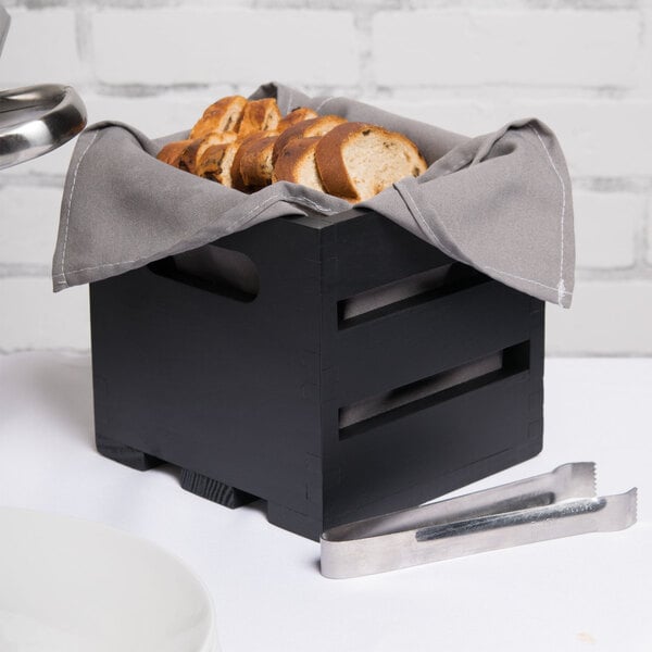 An American Metalcraft black wood crate with sliced bread inside.