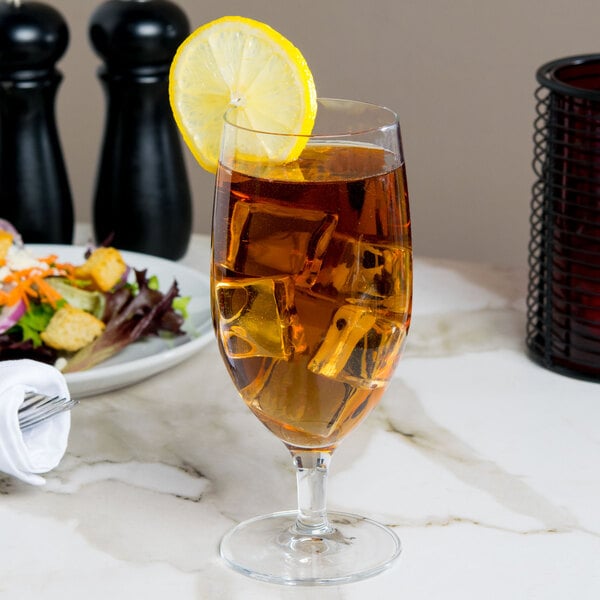 A Libbey Contour goblet filled with iced tea and a lemon slice on a table.