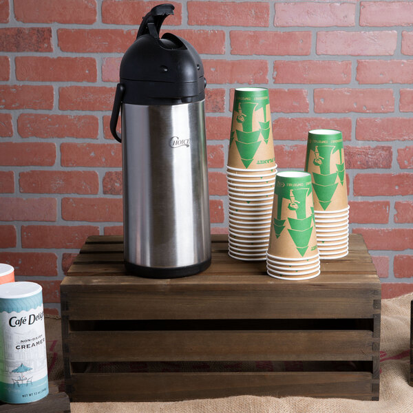 An American Metalcraft vintage wood crate with a white and green label holding white and green coffee cups and a thermos.