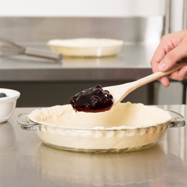 A person stirring Lucky Leaf Blueberry Pie Filling with a wooden spoon.