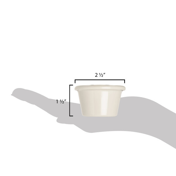 A hand holding a small ivory melamine ramekin with a handle.