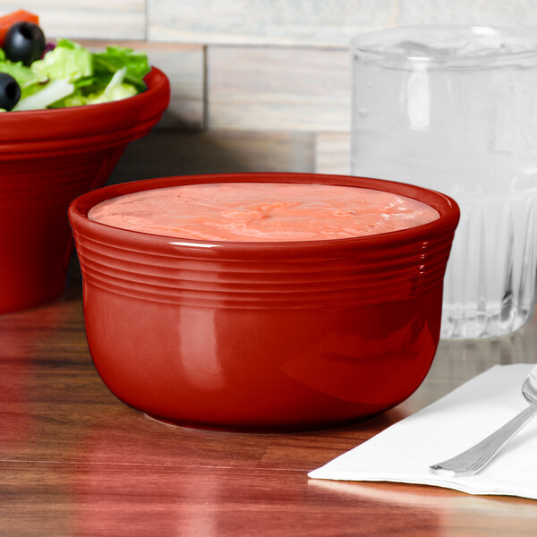 A red Fiesta China Gusto Bowl filled with food on a wood table.