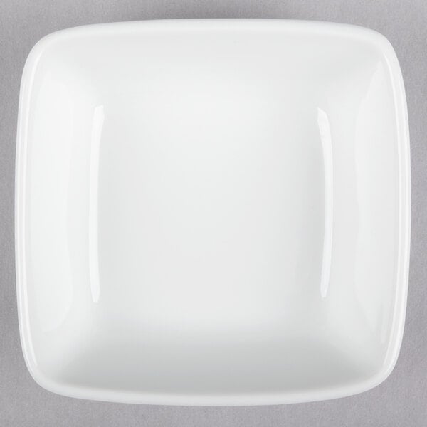 A Libbey Chef's Selection white square bowl on a gray surface.