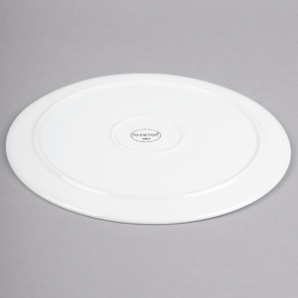 A white porcelain round tray with a black logo on the bottom.