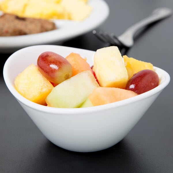 A Libbey white porcelain bowl filled with fruit on a table.