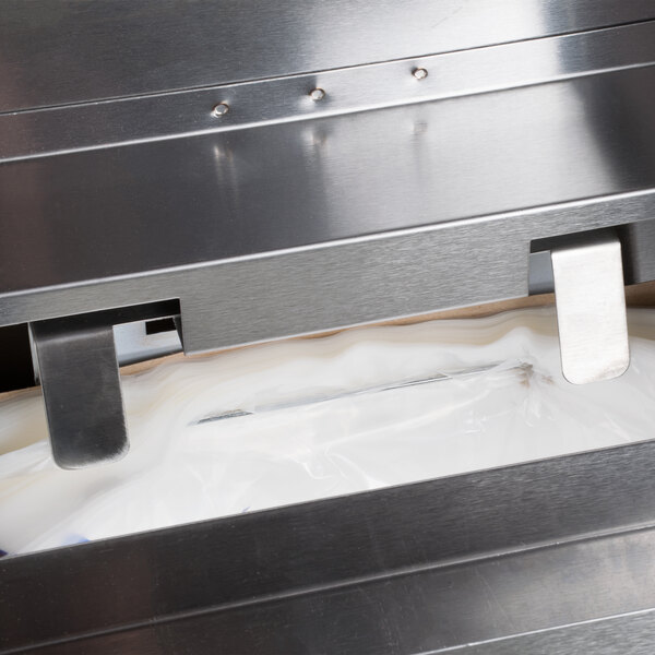 A Manitowoc stainless steel ice bagger holding plastic bags on a roll.