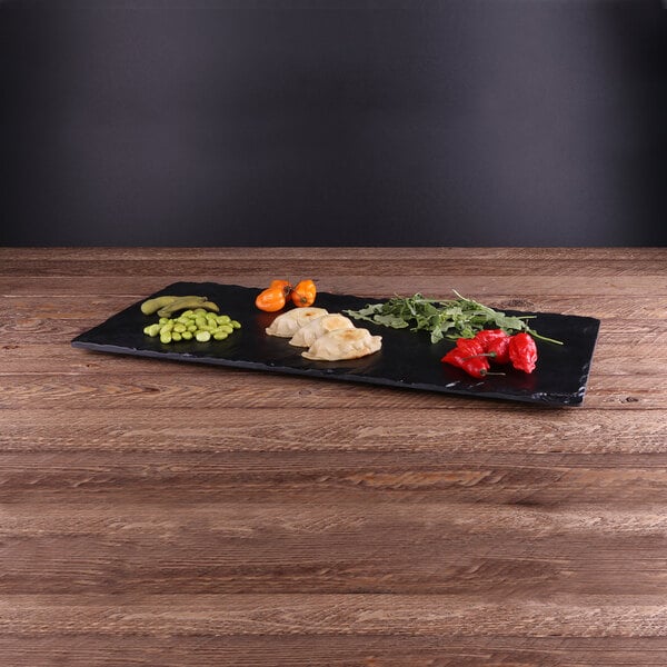 An Elite Global Solutions black faux slate melamine serving board with food on it.