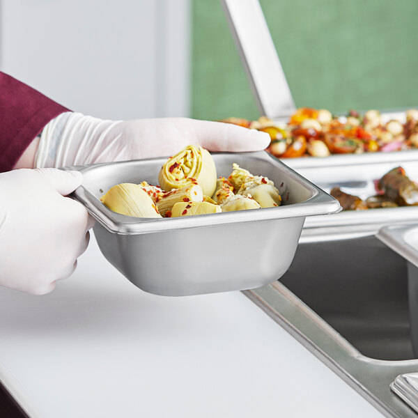 A person holding a Vollrath stainless steel tray of food.