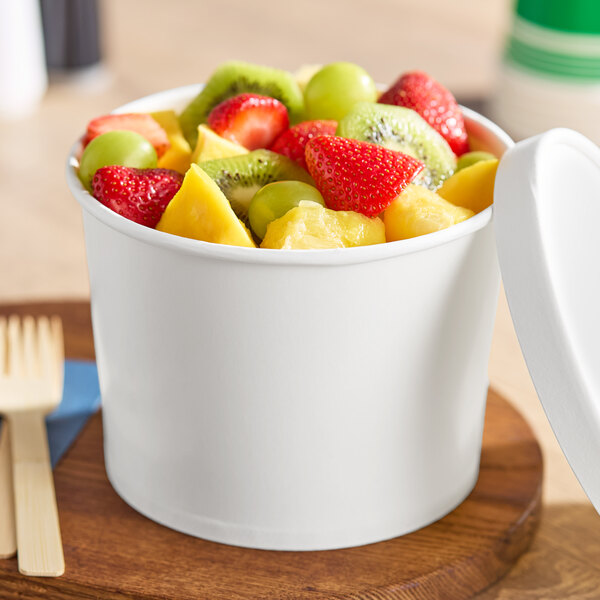 A white paper food cup with a lid, filled with assorted fresh fruit pieces.