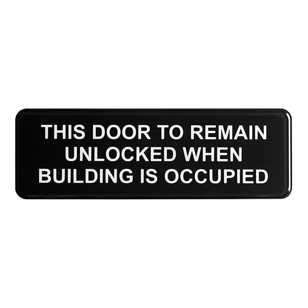 A black Tablecraft sign with white text that says "This door to remain unlocked when building is occupied"