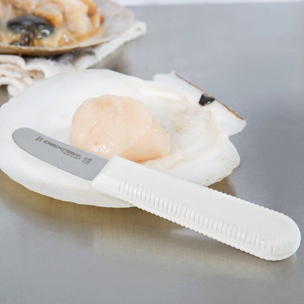A Dexter-Russell Sani-Safe scallop knife cutting a raw scallop on a shell.
