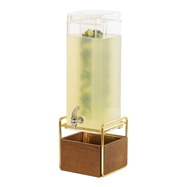 A Cal-Mil square beverage dispenser with a walnut and brass base on a wooden stand with a glass infusion chamber.