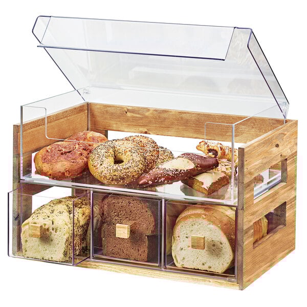 A wooden Cal-Mil bread display case with two tiers of bread in a glass case.
