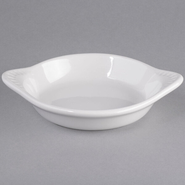 A Tuxton white china shirred egg dish with a handle.