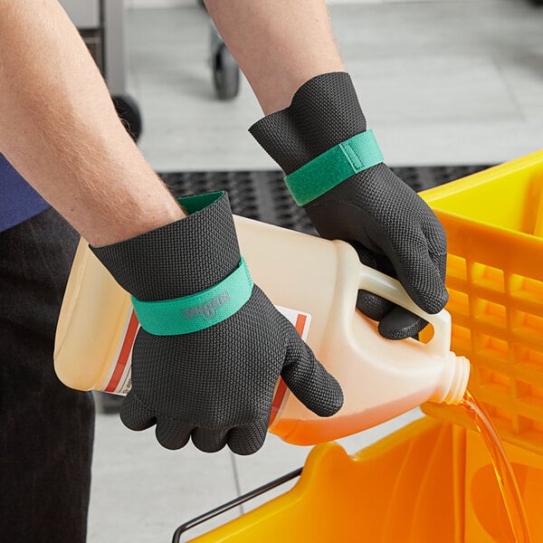 A person wearing Unger neoprene gloves pouring liquid into a plastic container.