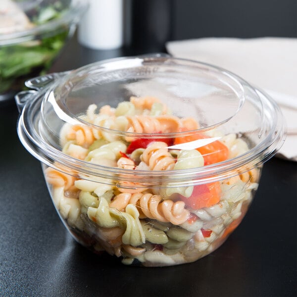 A Dart clear plastic bowl with pasta and a dome lid.