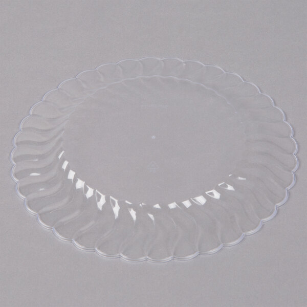 A Fineline Flairware clear plastic plate with a scalloped edge.