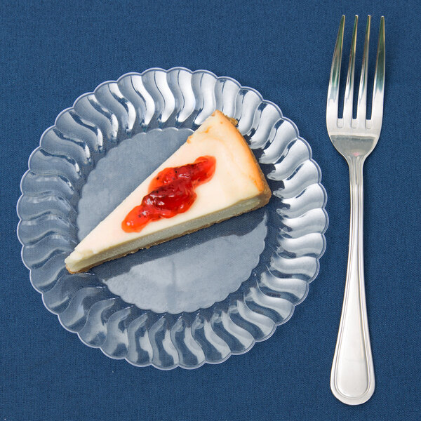 A slice of cheesecake on a clear Fineline Flairware plastic plate with a fork.
