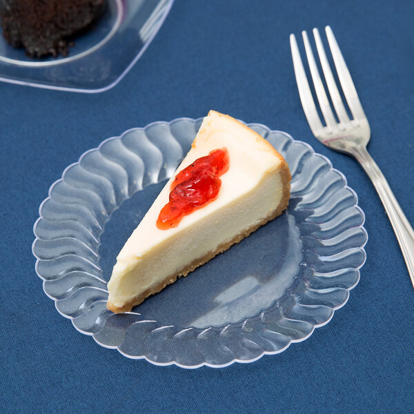 A slice of cheesecake on a clear Fineline Flairware plastic plate with a fork.