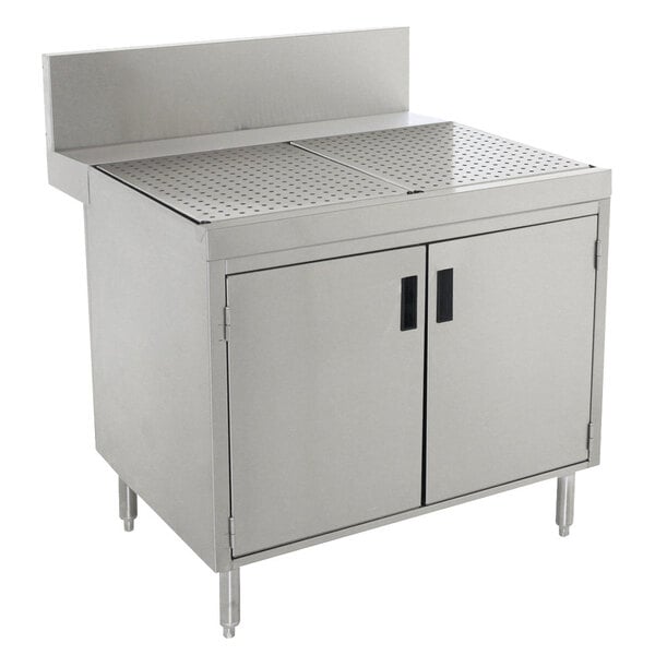 A stainless steel Advance Tabco Prestige Series drainboard cabinet with doors and a shelf.