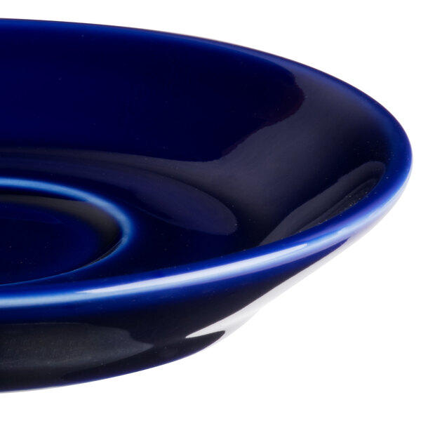 A close up of a Tuxton cobalt cappuccino saucer with a white rim.