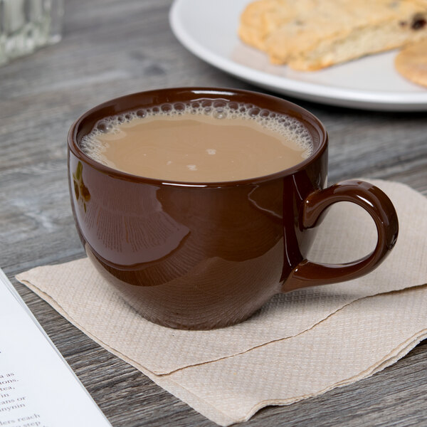 A brown Tuxton mahogany cappuccino cup on a napkin next to cookies.