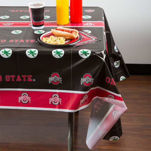 A table with an Ohio State University table cover and food and drinks on it.