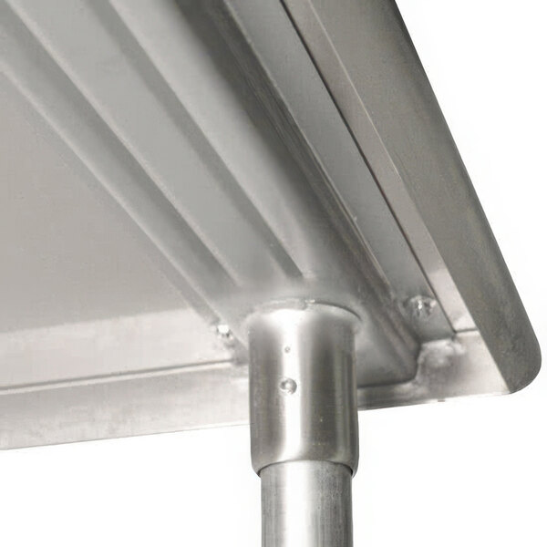 A close-up of a stainless steel Advance Tabco work table with a metal edge.