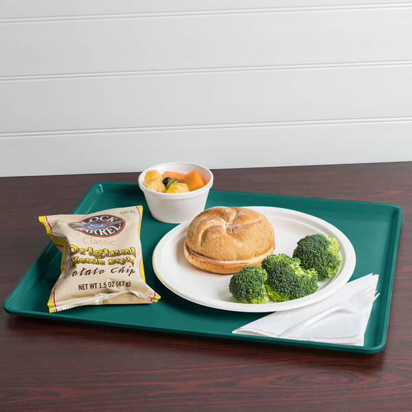 A teal Cambro dietary tray with a sandwich, broccoli, and potato chips.