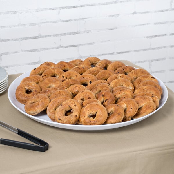 A white Siciliano display platter with a plate of bagels on a table.