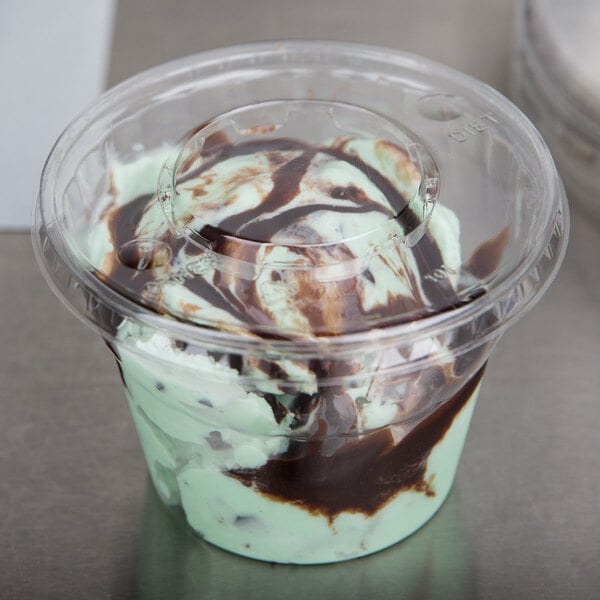 A WNA Comet clear plastic lid on a cup of chocolate and mint ice cream.