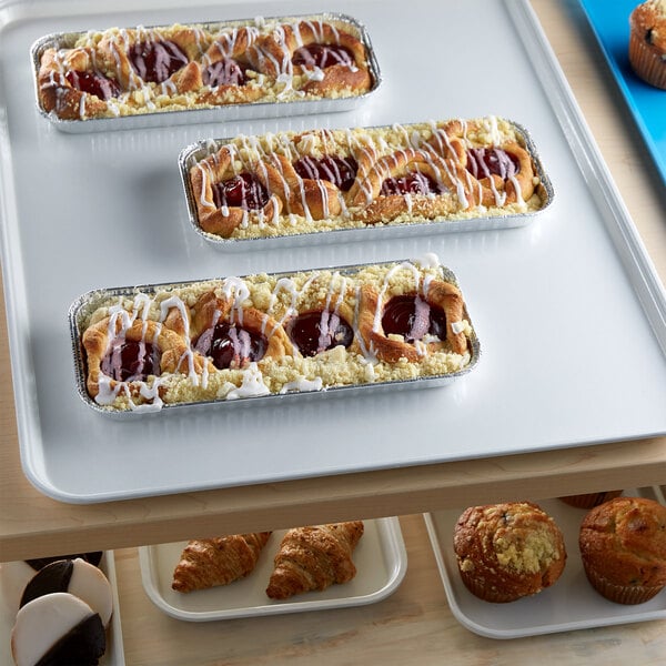 A white Cambro market tray with pastries and muffins on a table.