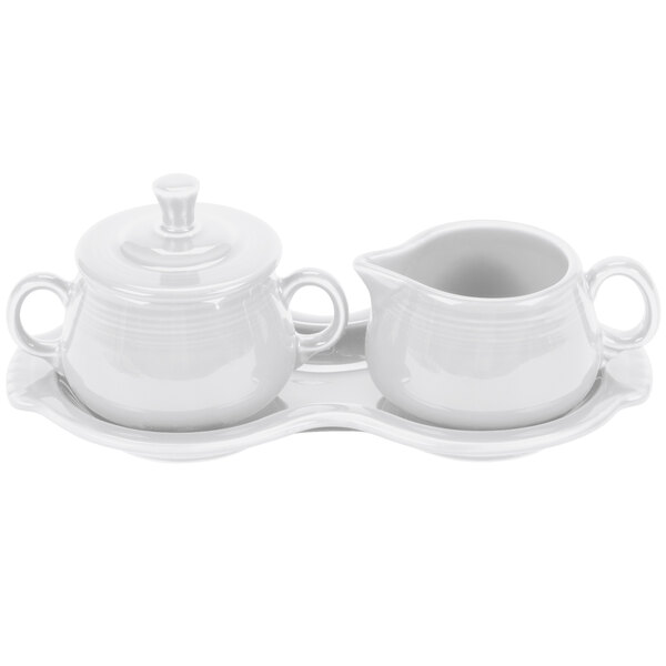 A white porcelain Fiesta sugar and creamer tray set with a creamer on a saucer and a sugar bowl.