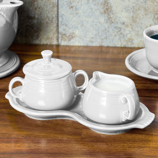 A white Fiesta sugar and creamer tray set on a table.