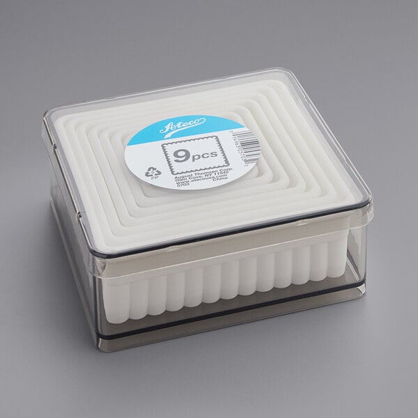 A plastic container with white foam inside holding Ateco fluted square cutters.